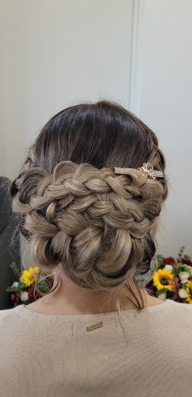 A thick Dutch braid wound into a low bun with a jewelled clip, seen from behind