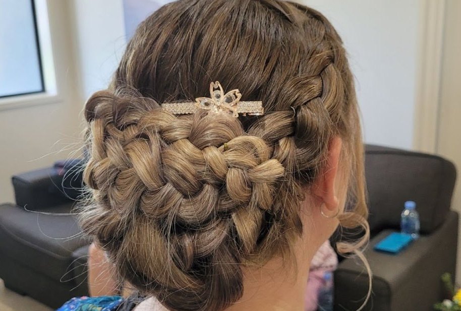 A plaited updo with a rose-gold butterfly clip, styled for a special occasion