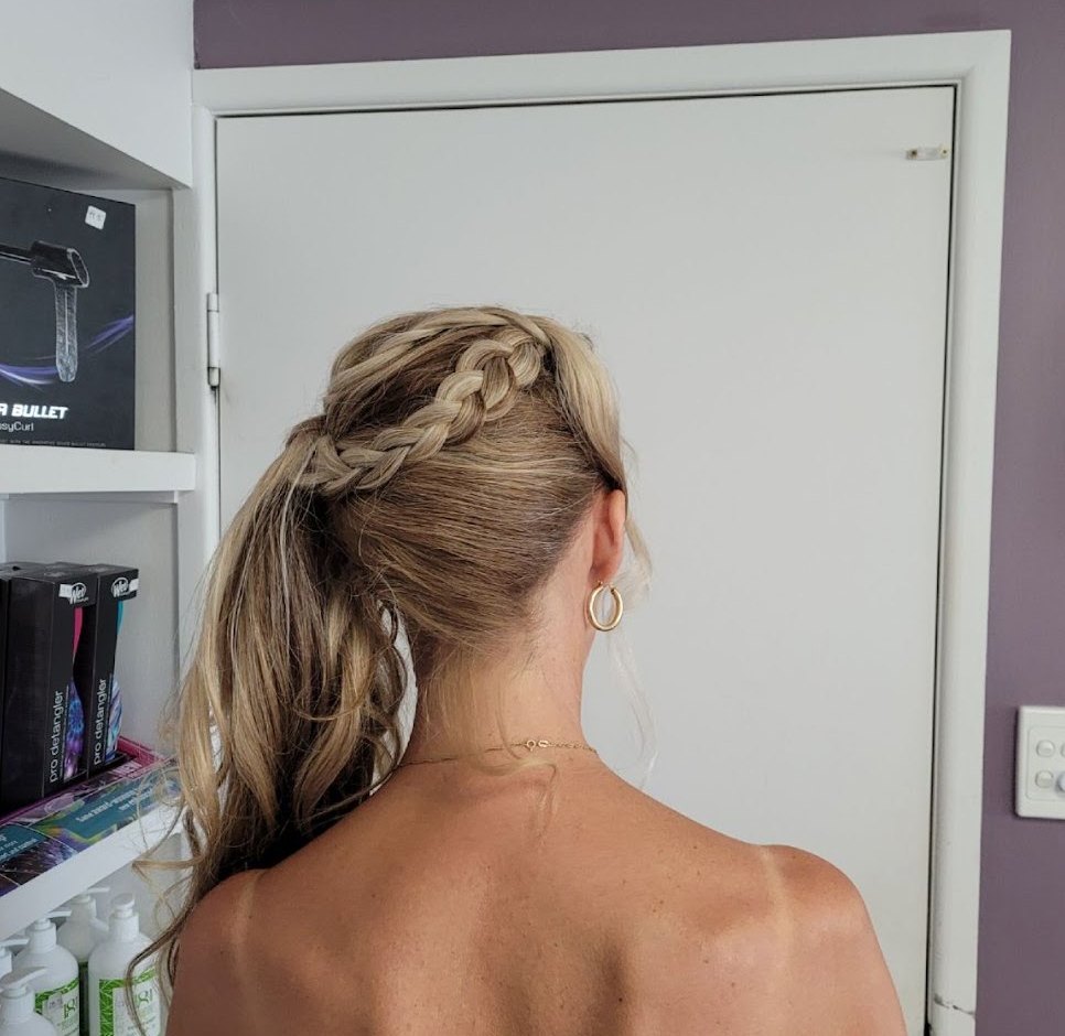 A side braid sweeping into a low ponytail, seen from behind