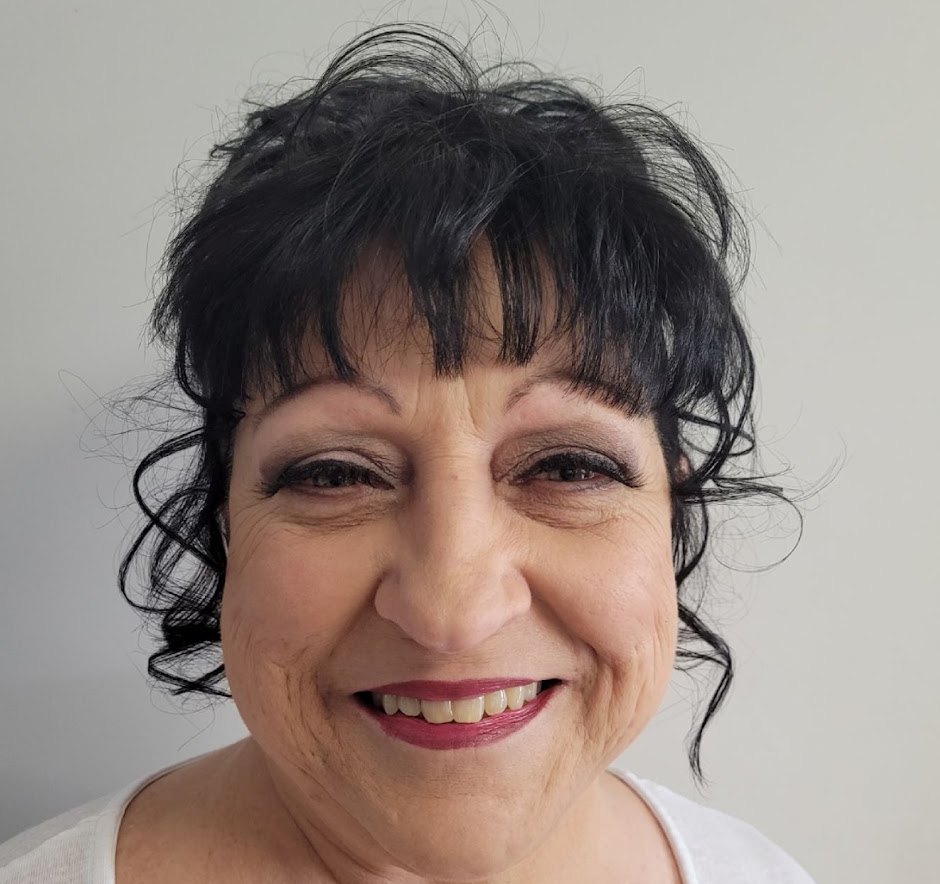 A smiling client with a curly fringe and finished make-up