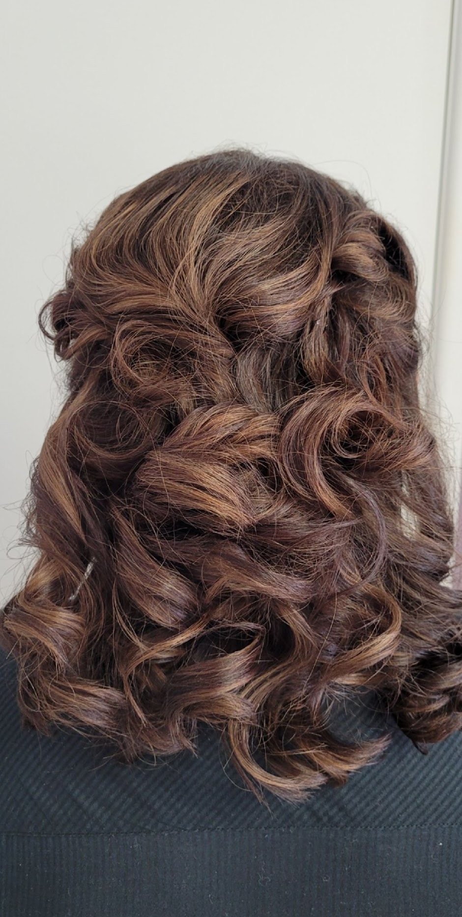 Shoulder-length brunette hair set in glossy, bouncy curls, seen from behind
