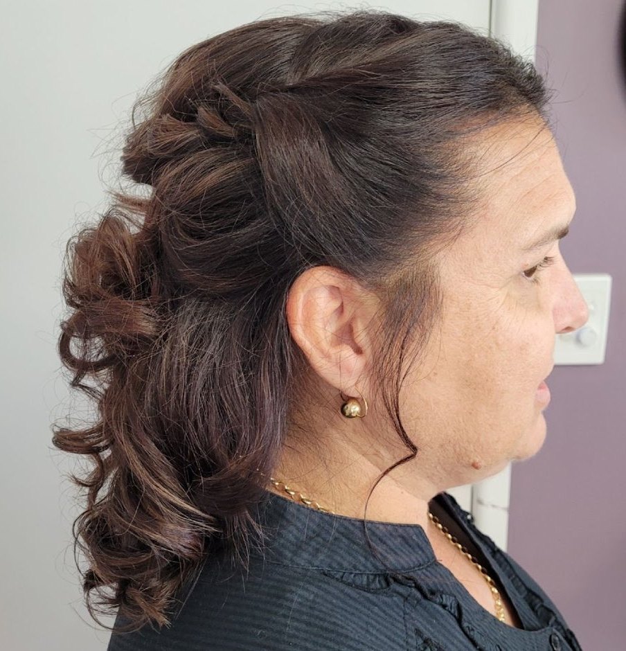 Brunette half-up style with a twisted crown and loose curls, in profile